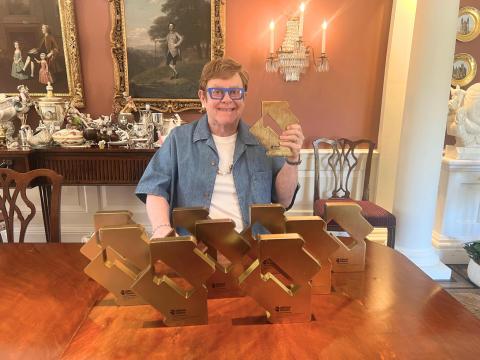 Elton John poses with 10 Official Number 1 Album Awards from Official Charts